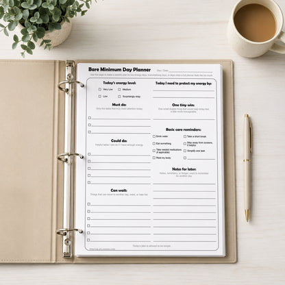 Bare Minimum Day Planner Printable page in a binder on a desk with a cup of coffee and plant.