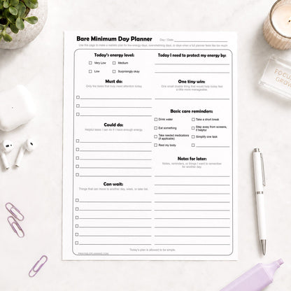 Bare Minimum Day Planner - Printable Page shown on a light desk with earbuds, paperclips, a plant, candle, highlighter, and a pen.