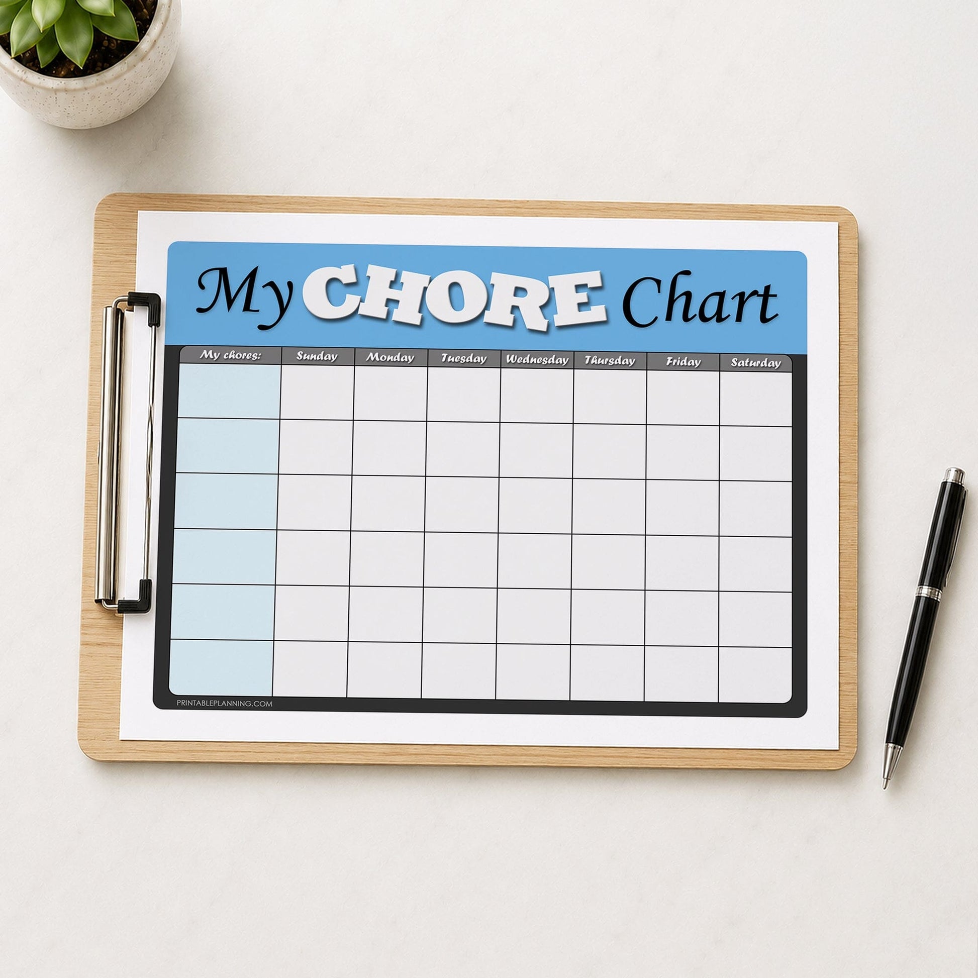 A wooden clipboard holding a printed 'My CHORE Chart' page with a blue header and grid, styled on a white surface with a small plant in the top left and a black pen on the right.