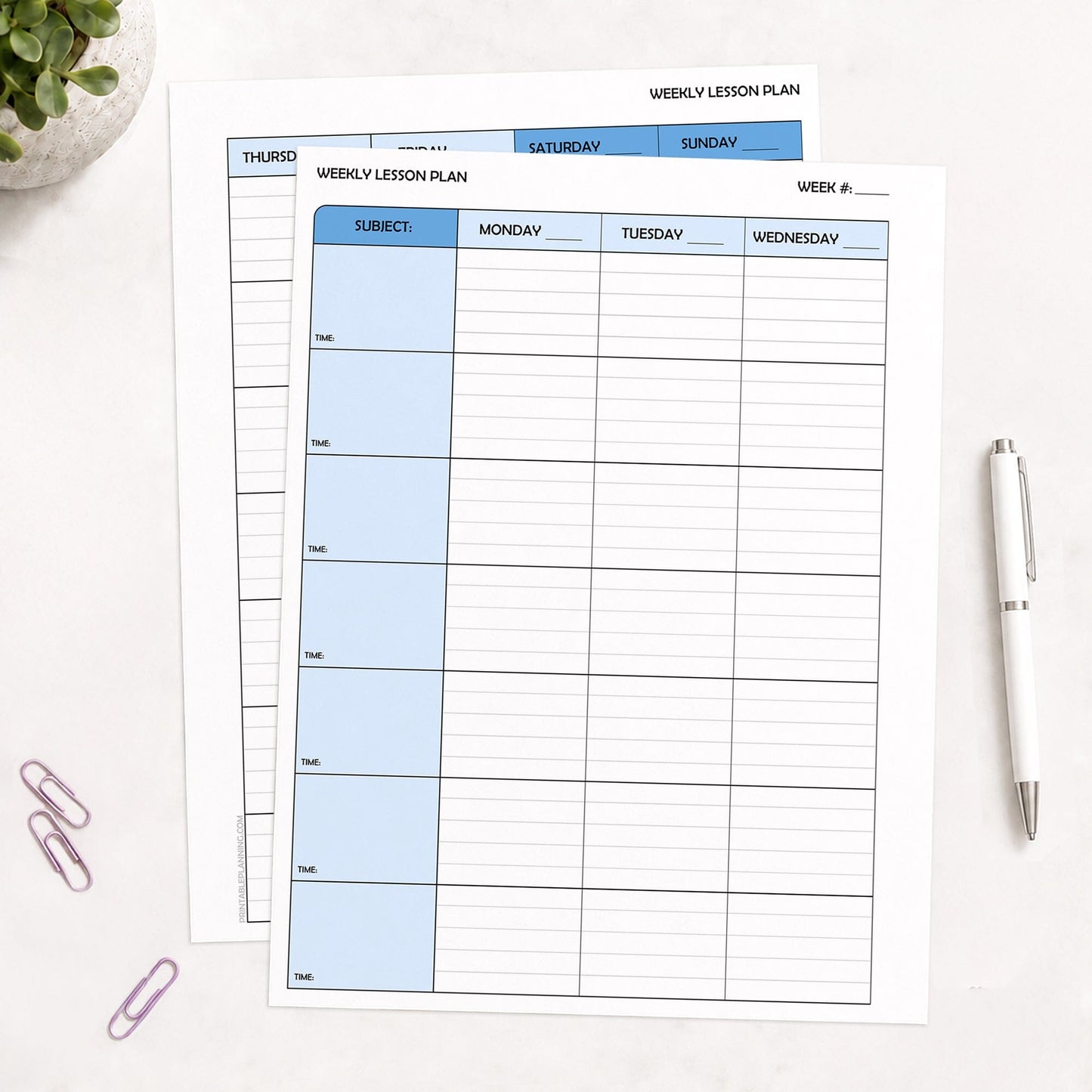Two front and back printed Blue Weekly Lesson Plan Pages for Teachers (printable) pages shown on a table with a plant, paperclips, and a pen.