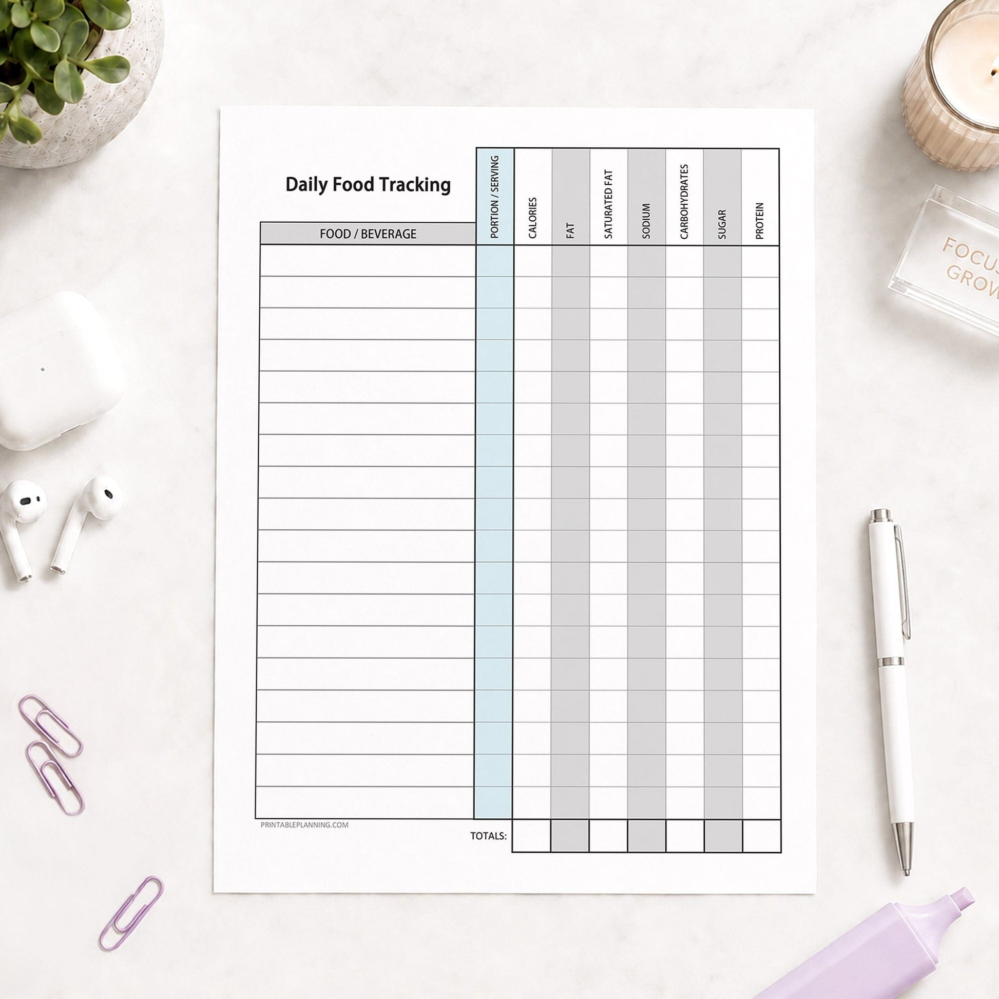 Daily Food Content Tracking Sheet (printable page) shown on a desk with earbuds, paperclips, plant, highlighter, and a pen.