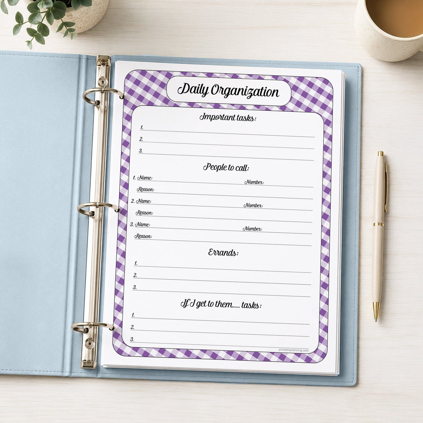 A printed purple gingham Daily Planner for Priorities, Calls, Errands & Tasks (printable) page shown in a light blue binder on a desk with a plant, coffee, and a pen.