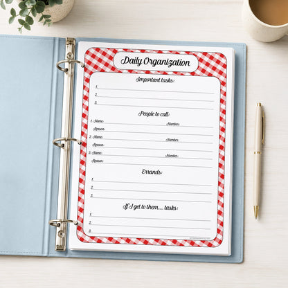 A printed red gingham Daily Priority Planner with Calls, Errands & Tasks (printable) page shown in a light blue binder on a desk with a plant, coffee, and a pen.