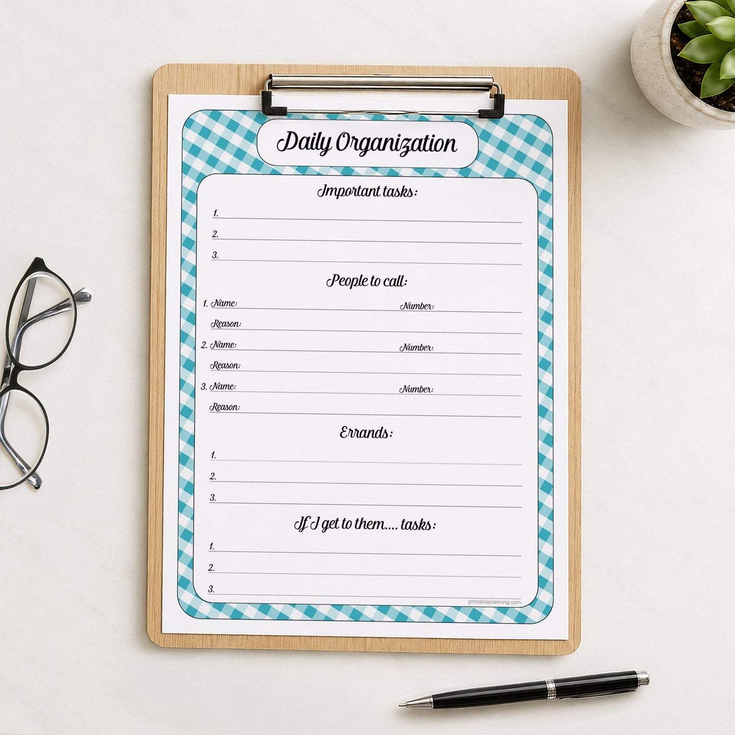 A printed turquoise gingham Daily Planner for Priorities, Calls, Errands & To-Dos (printable) page shown on a wooden clipboard on a table with a plant, glasses, and a pen.