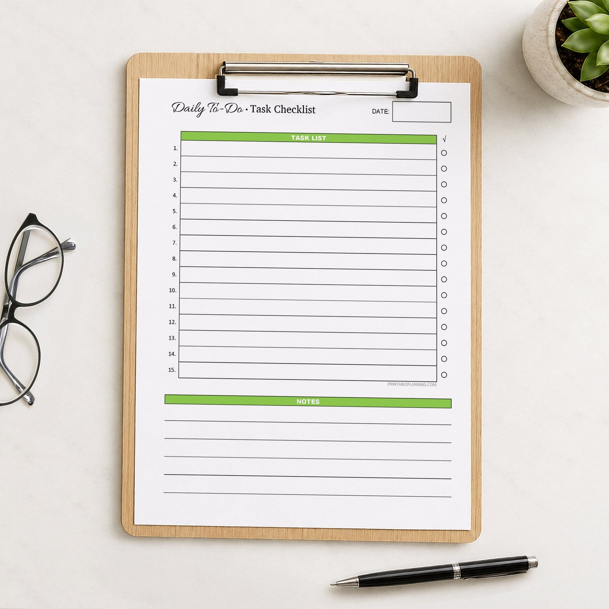 A printed Daily To-Do List & Task Checklist (printable) page, in green, shown on a wooden clipboard on a table with a plant, glasses, and a pen.