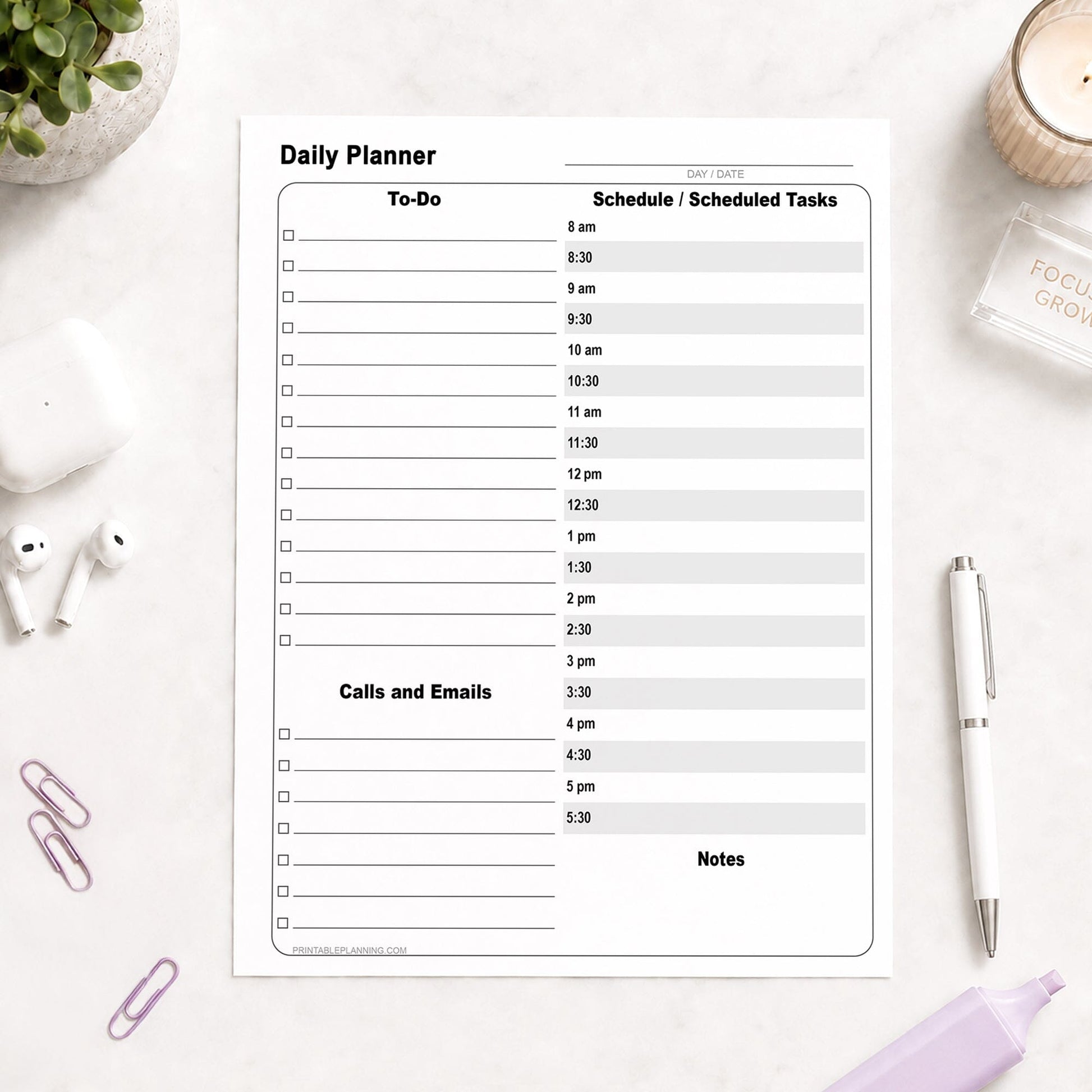 A printed Daily Work Planner with To-Do List and Schedule (printable page) shown on a desk with a plant, earbuds, paperclips, highlighter, and a pen.