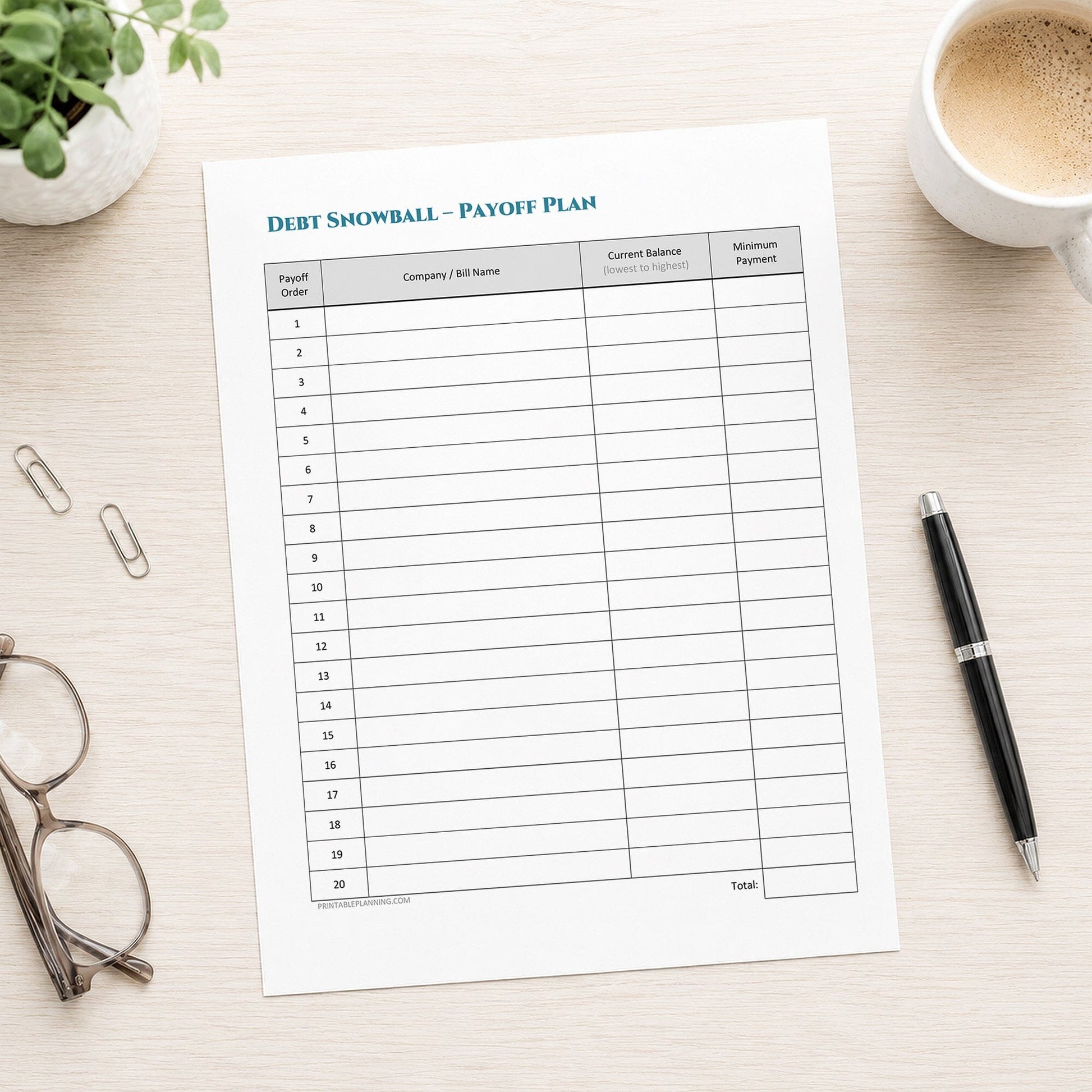 A debt snowball payoff plan worksheet sheet displayed on a light wood desk with a coffee cup, glasses, paper clips, and a pen nearby.