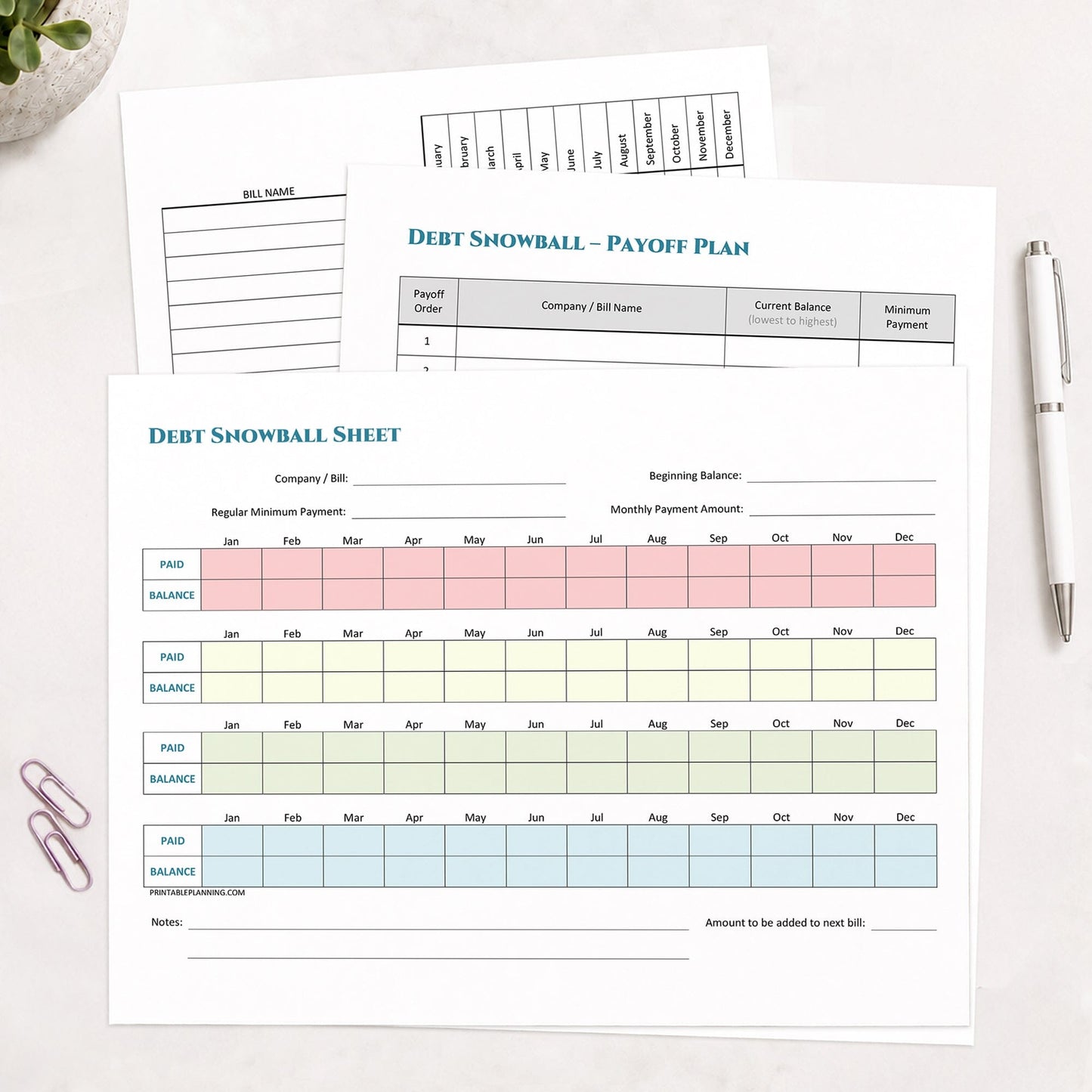 Three printed pages of the printable Debt Snowball, Debt Payoff Plan & Yearly Bill Tracker Bundle shown on a desk with a plant, paperclips, and a pen.