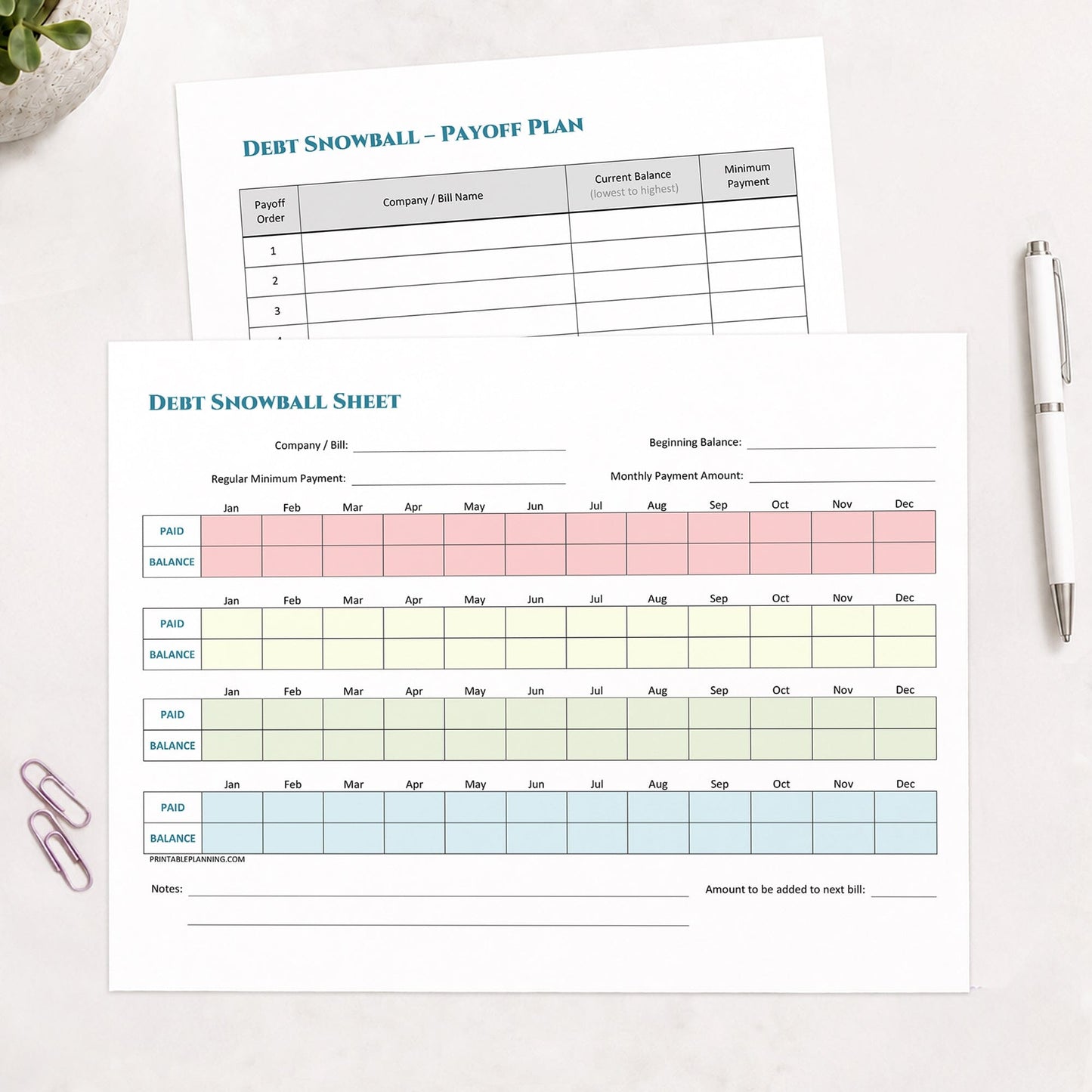 The two printed pages from the printable Debt Snowball Tracker & Debt Payoff Plan Bundle shown on a table with a plant, paperclips, and a pen.