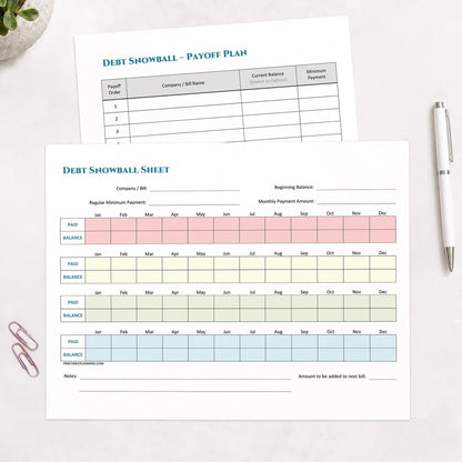 The two printed pages from the printable Debt Snowball Tracker & Debt Payoff Plan Bundle shown on a table with a plant, paperclips, and a pen.