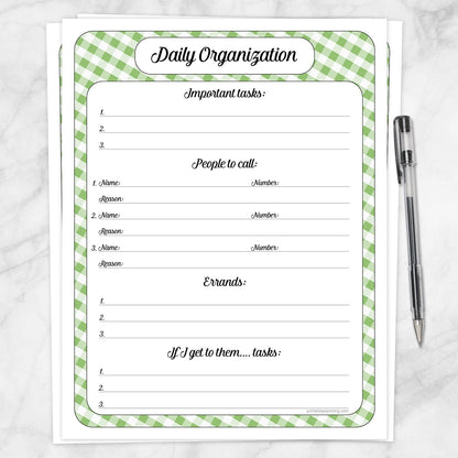 The printable Green Gingham Daily Organization Planner with Priorities, Calls & Errands page shown on a marble surface with a pen.