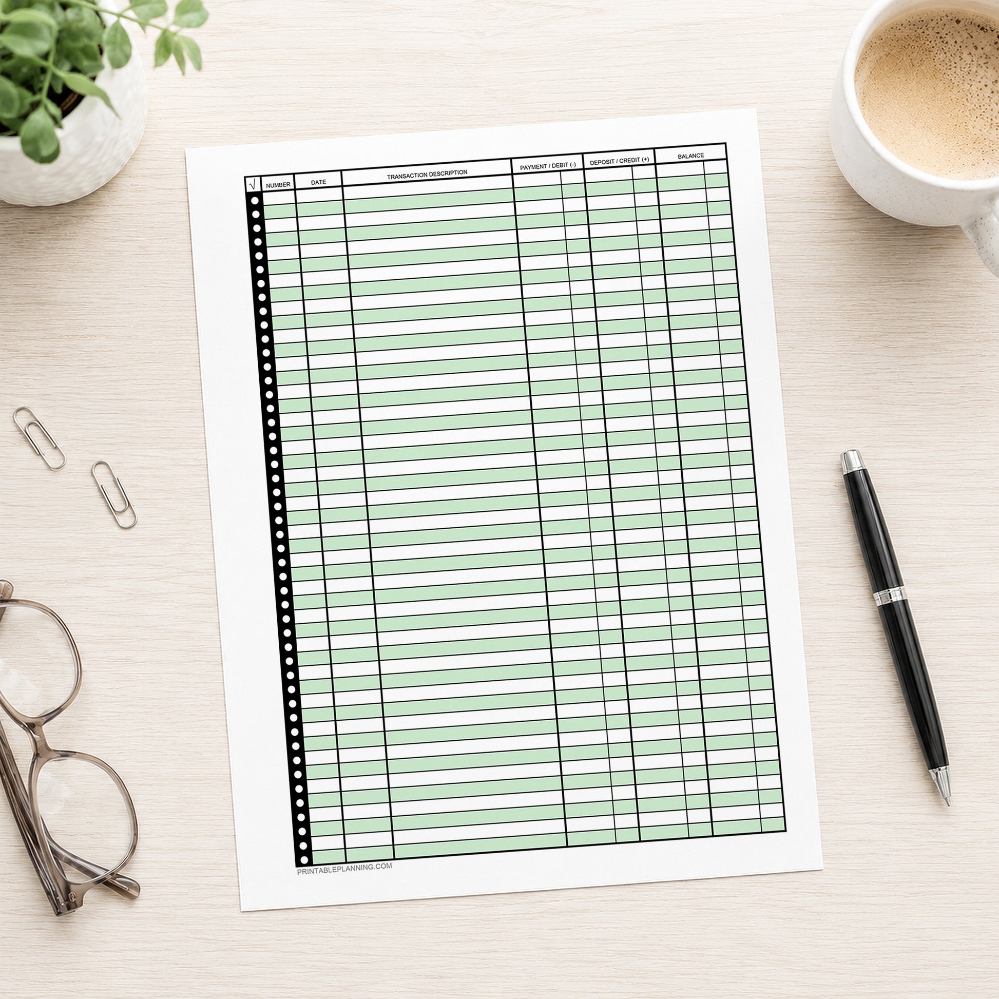 Green Printable Check Register - Full-Page Transaction Tracker shown on a desk with glasses, coffee, a plant, and a pen.