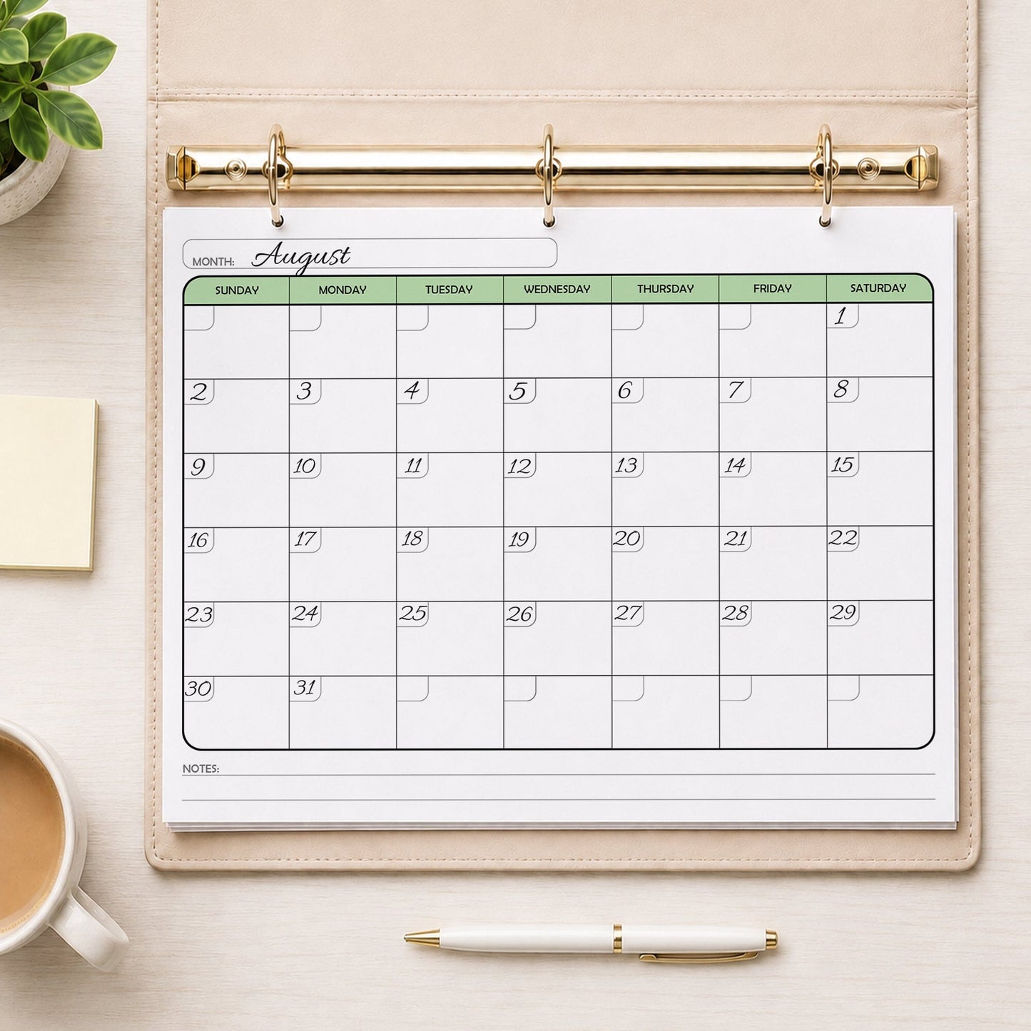 The printed Undated Monthly Calendar - Green Full-Page Planner (printable) page shown with example writing in a beige binder on a desk with a plant, sticky notes, coffee, and a pen.