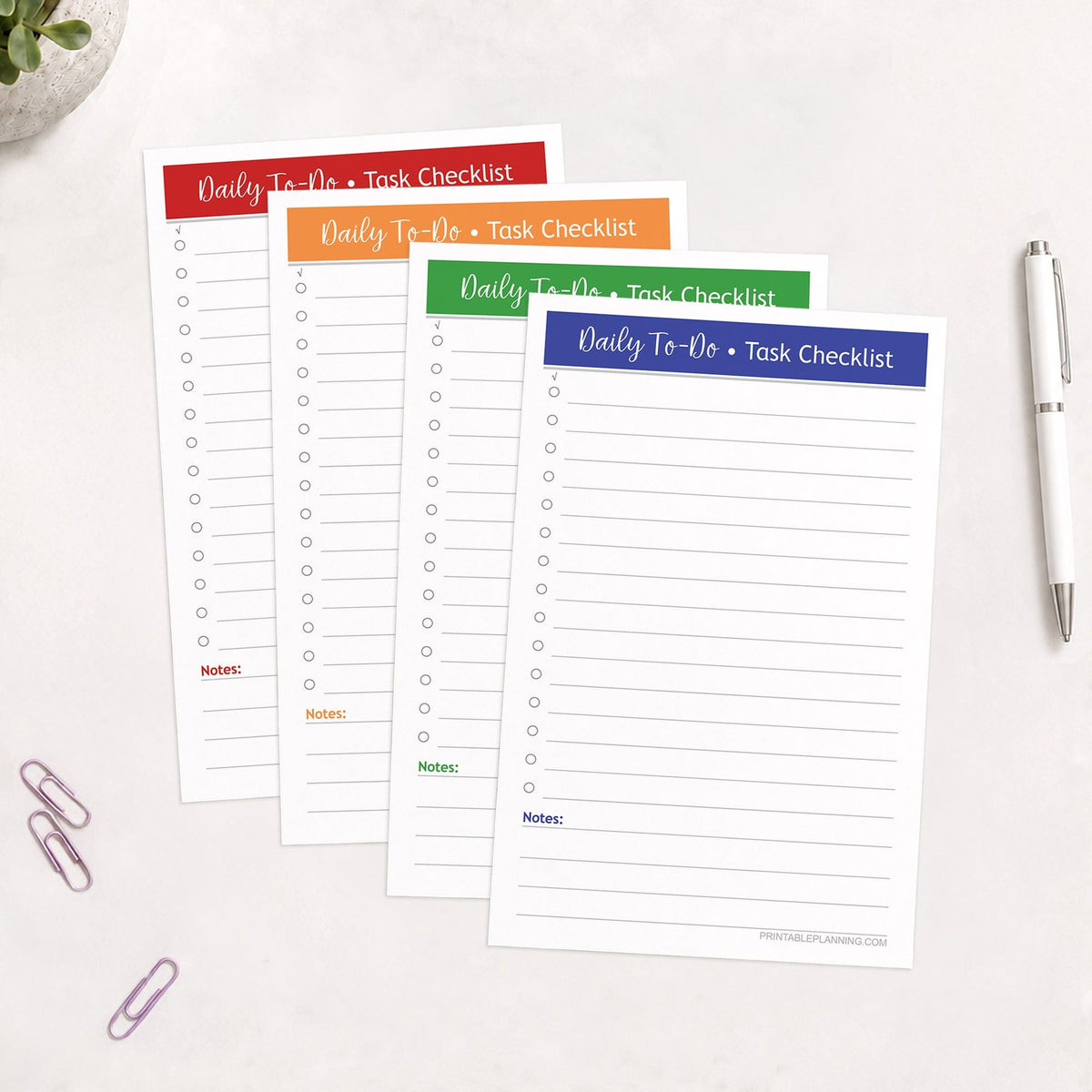 Printed pages of the printable Half-Page Daily To-Do List & Task Checklist Bundle with 4 Bold Colors, shown on a table with a plant, paperclips, and a pen.