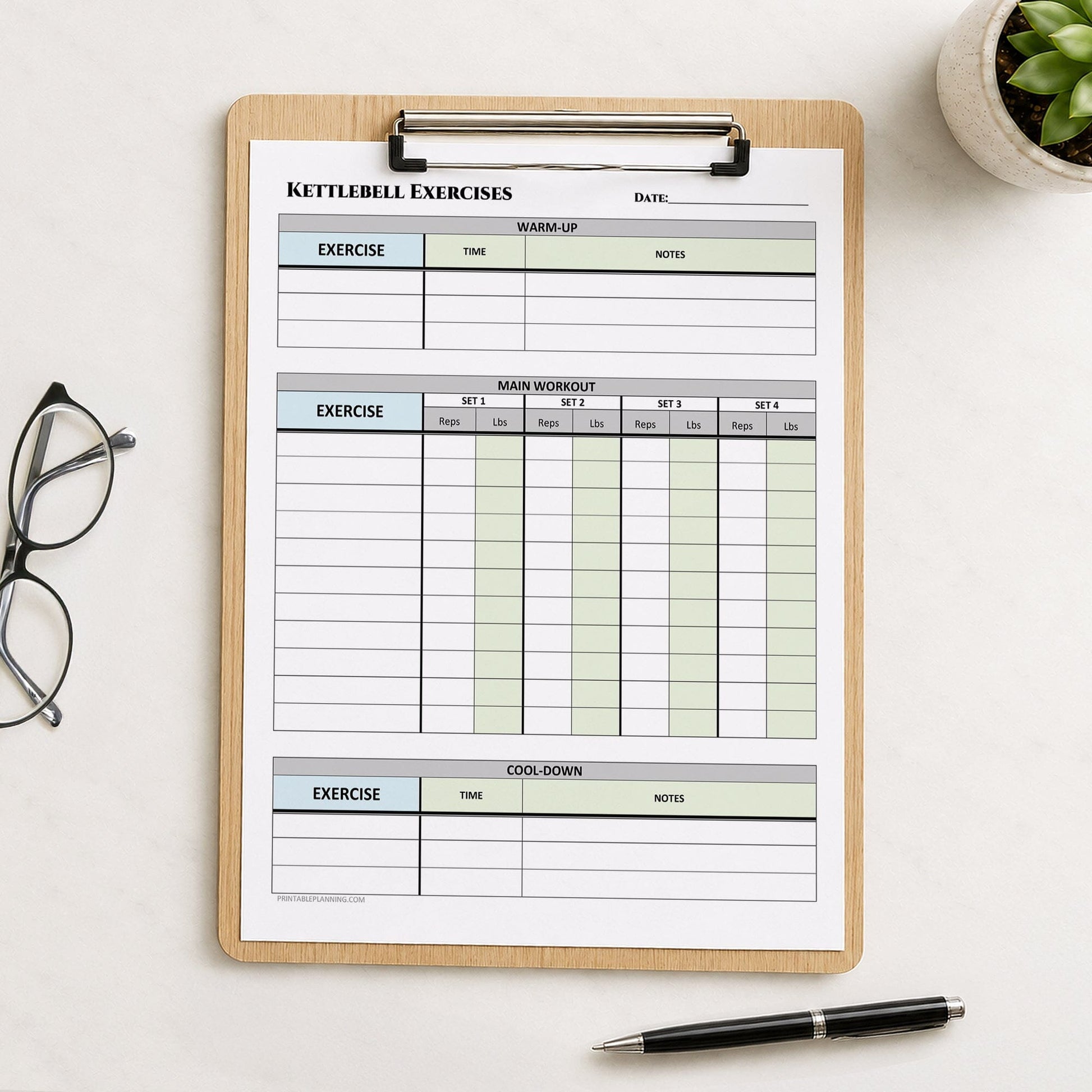 A wooden clipboard holding a printable kettlebell exercise tracker sheet, styled on a light surface with a pair of eyeglasses, a small succulent, and a black pen nearby.