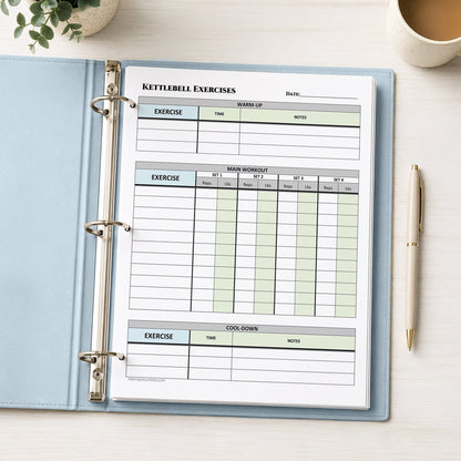 A light blue ring binder notebook open on a light desk, showing a printed 'Kettlebell Exercises' tracking sheet with tables for warm-up, main workout, and cool-down. A pen, plant, and cup are visible around it.
