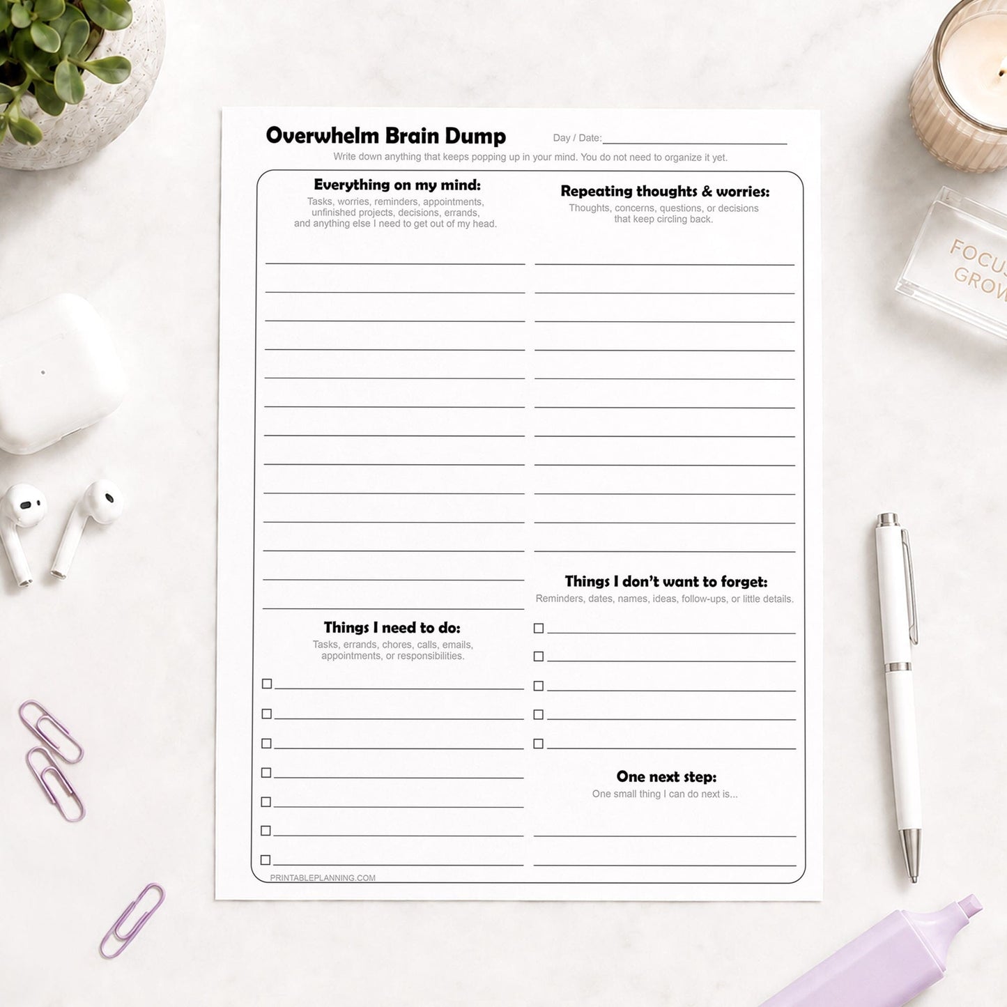 Printable Overwhelm Brain Dump Worksheet shown on a light desk with earbuds paperclips, a plant, highlighter, and a pen.