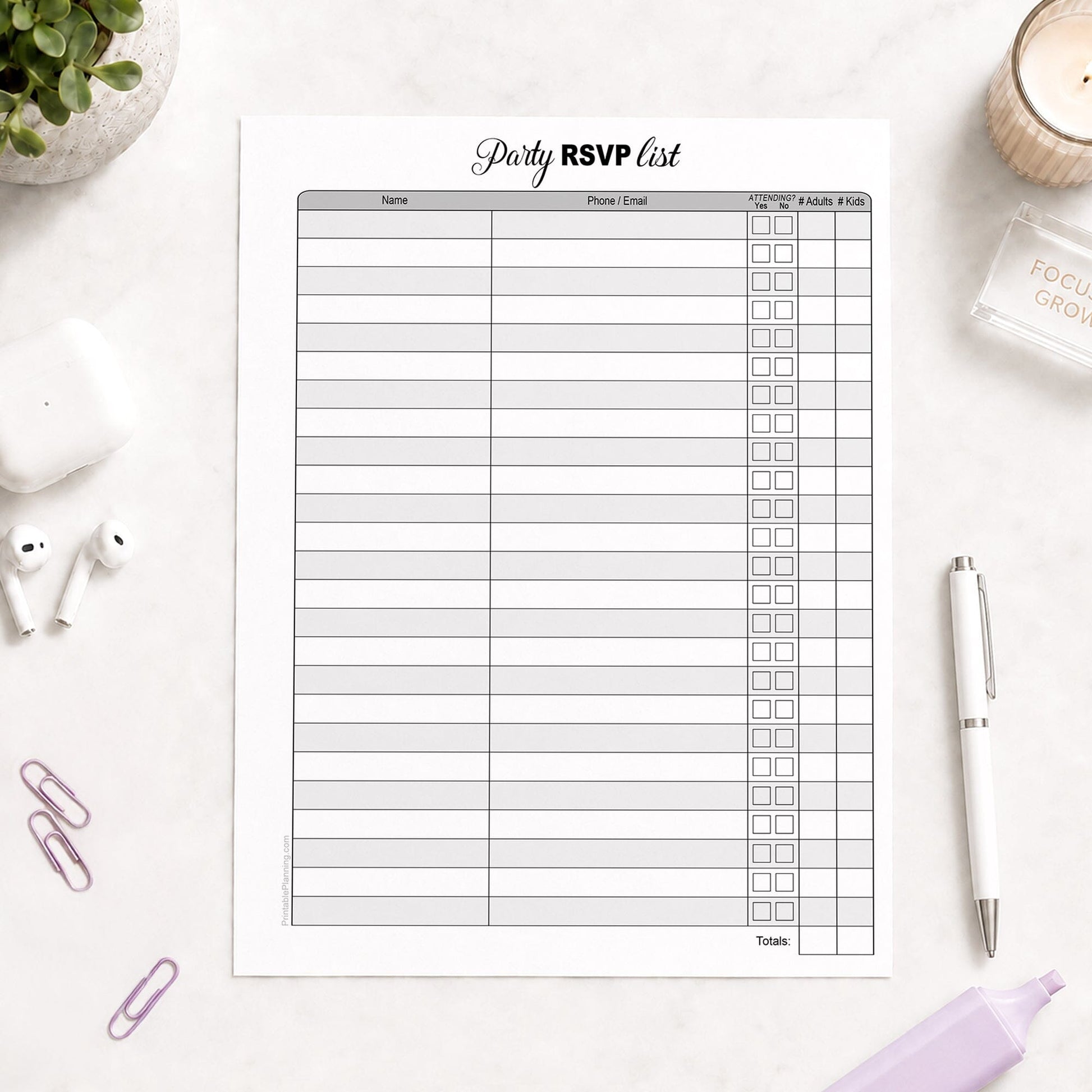 Printable Party RSVP List shown on a light desk with earbuds, paperclips, highlighter, plant, and a pen.