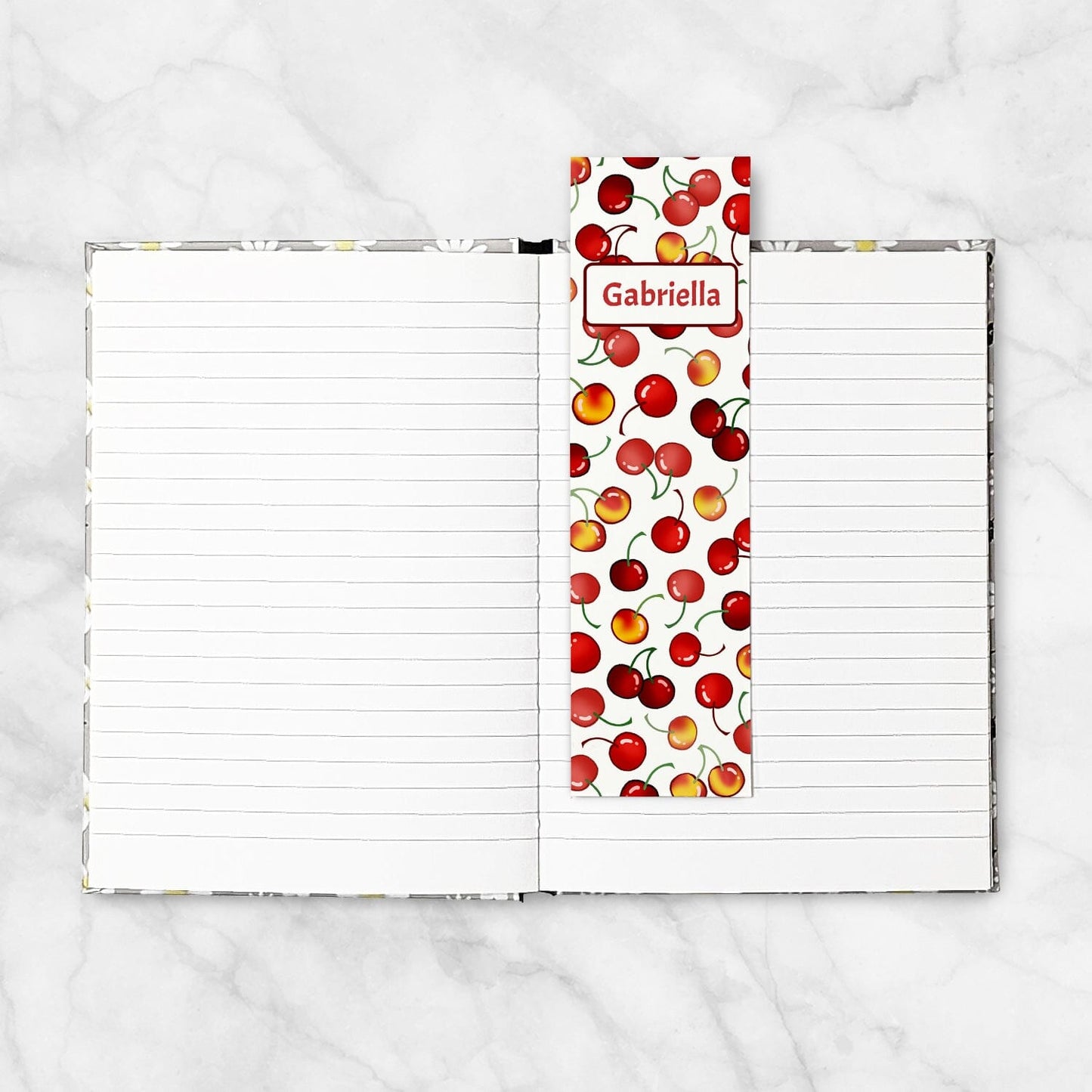 Printable Personalized Cherries Bookmarks at Printable Planning. Example of bookmark in an open hardcover notebook.