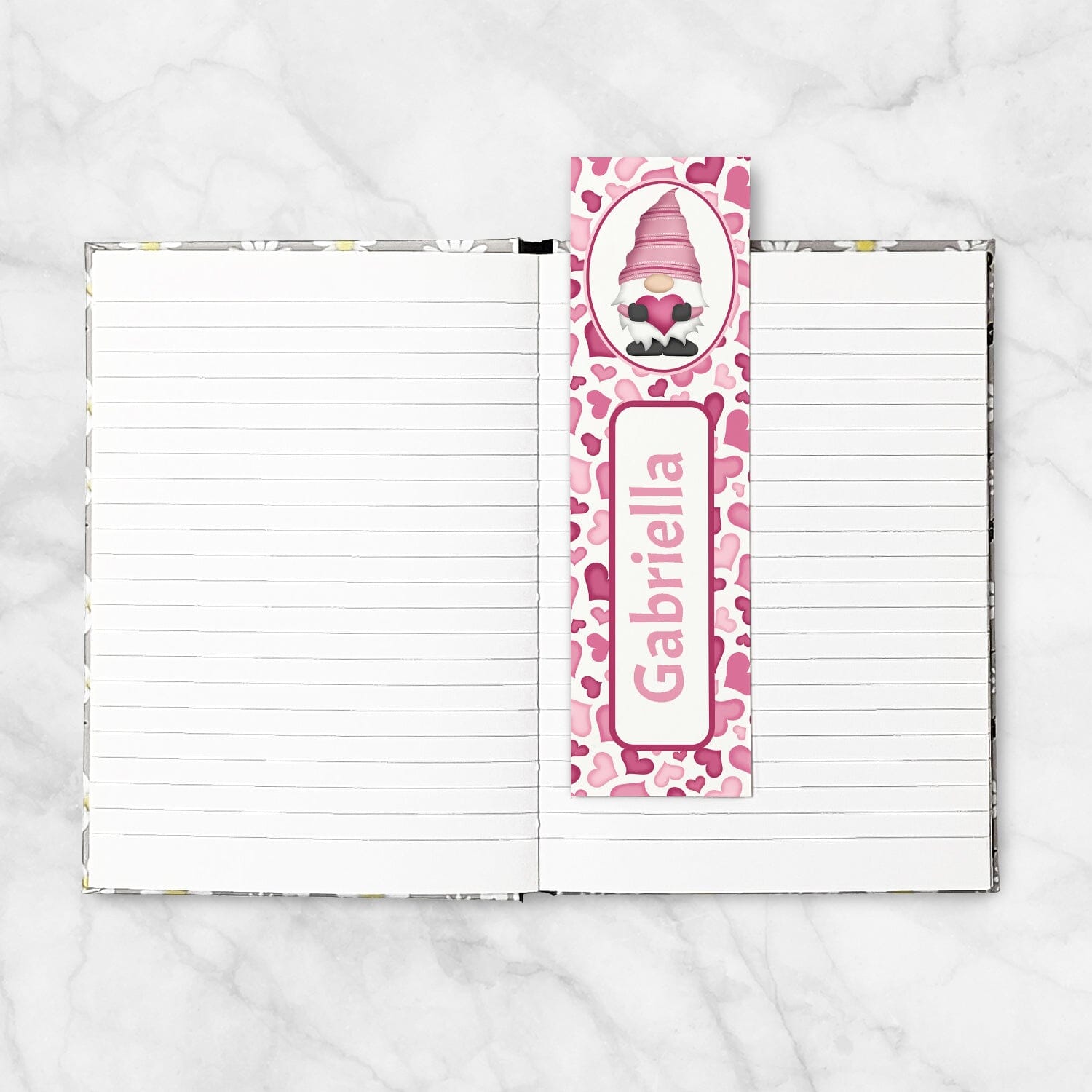 Notebook with a pink gnome-themed bookmark on a white marble background