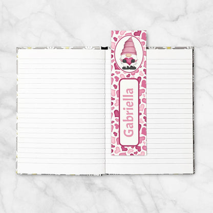 Notebook with a pink gnome-themed bookmark on a white marble background