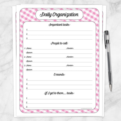 The printable Pink Gingham Daily Planner with Priorities, Calls & Errands page shown on a marble surface with a pen.