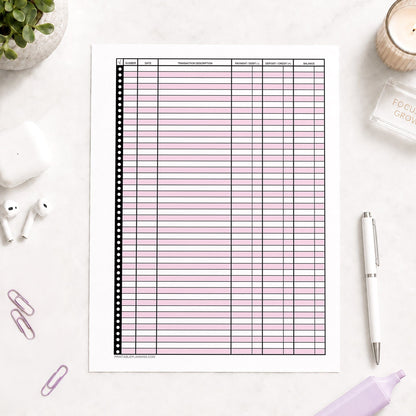 Pink Printable Check Register - Full-Page Transaction Tracker shown on a light desk with earbuds, paperclips, highlighter, plant, and a pen.