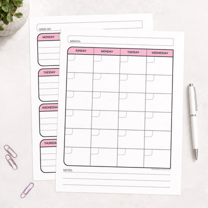 The printed Pink Undated Monthly & Weekly Planner (printable) Pages shown on a desk with a plant, paperclips, and a pen.