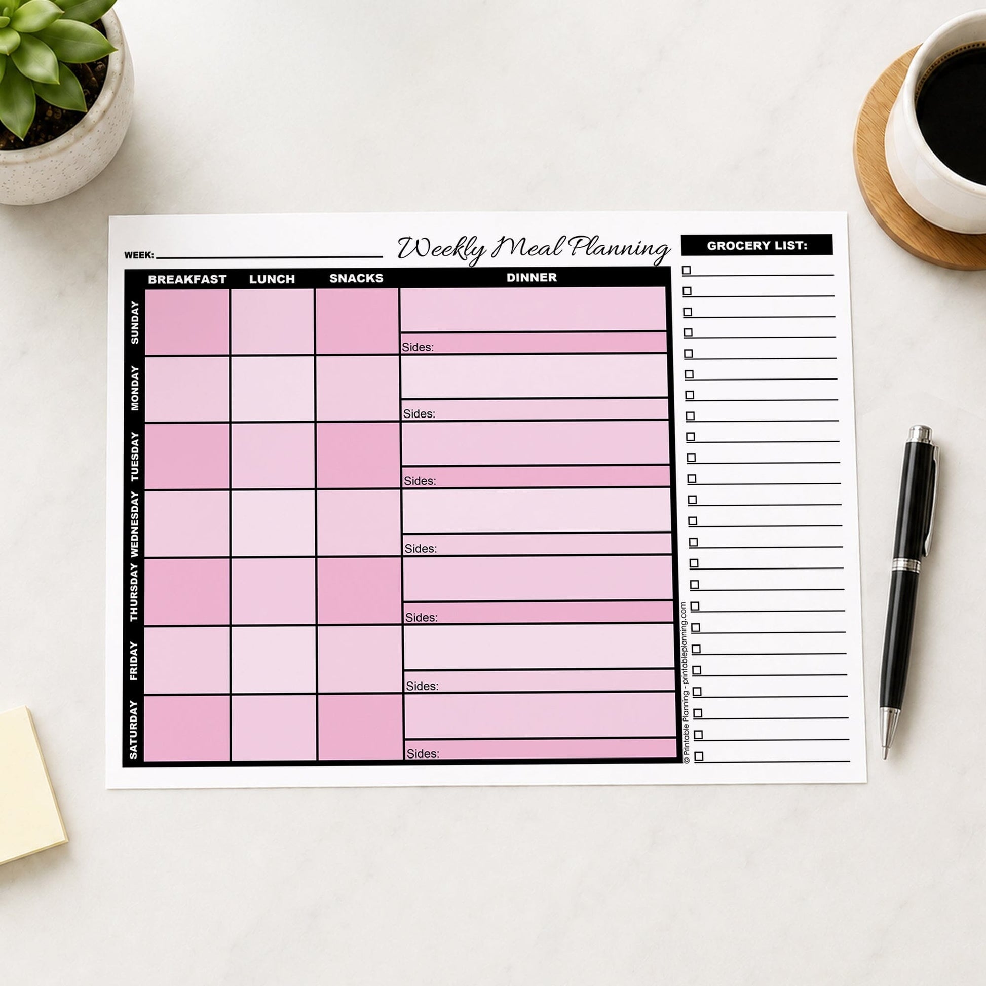 A printed Pink Weekly Meal Planner with Grocery List (printable page) shown on a desk with a plant, sticky notes, coffee, and a pen.