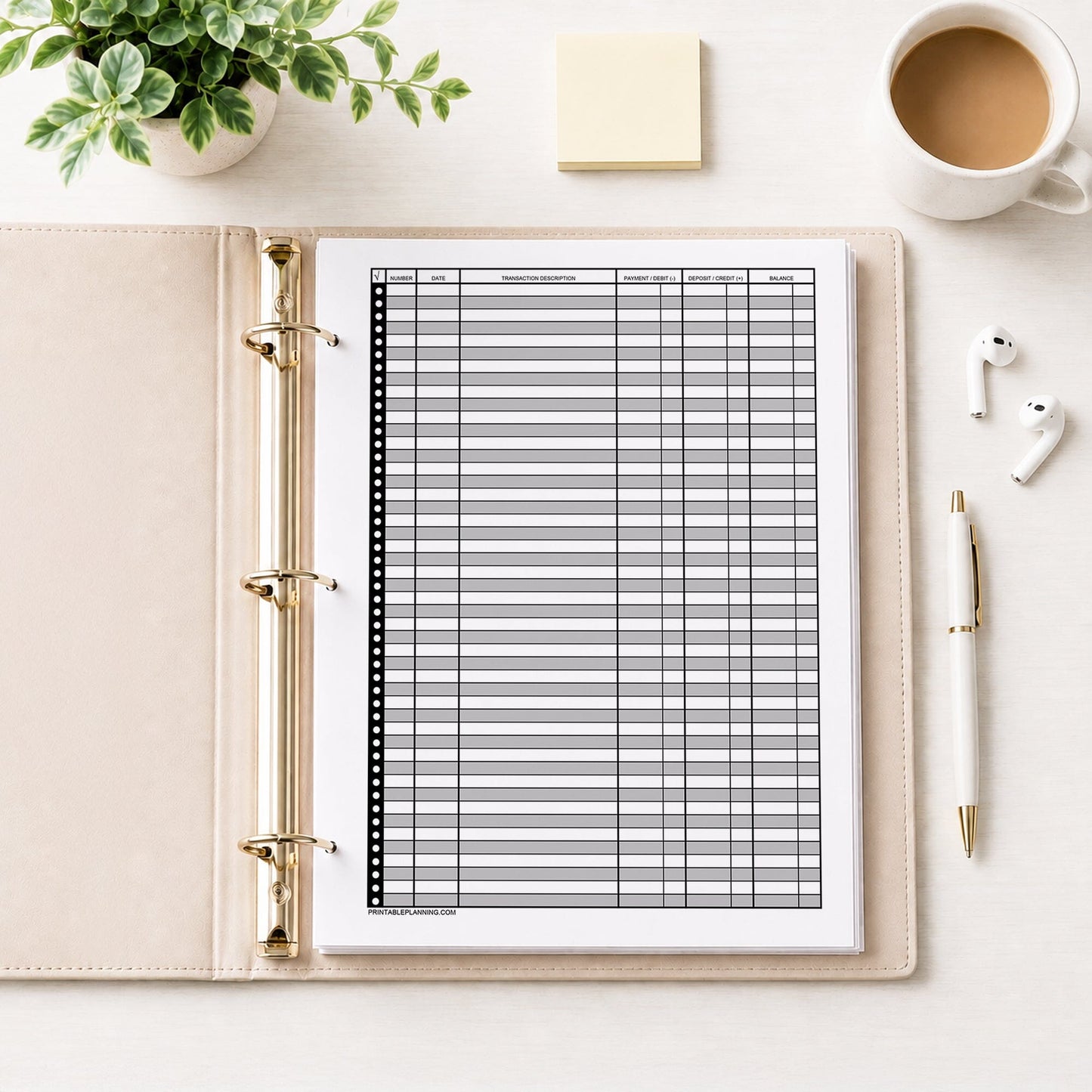 Printable Check Register - Full-Page Financial Transaction Tracker shown in a beige binder on a desk with earbuds, coffee, notes, a plant, and a pen.
