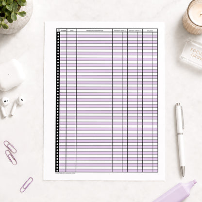 Purple Printable Check Register - Full-Page Transaction Tracker shown on a light desk with earbuds, paperclips, highlighter, plant, and a pen.