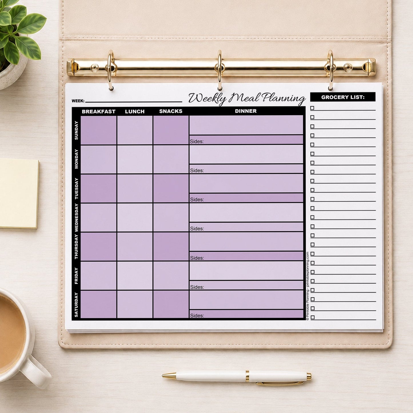 A printed Purple Weekly Meal Planner with Grocery List (printable page) shown in a beige binder on a table with a plant, sticky notes, coffee, and a pen.