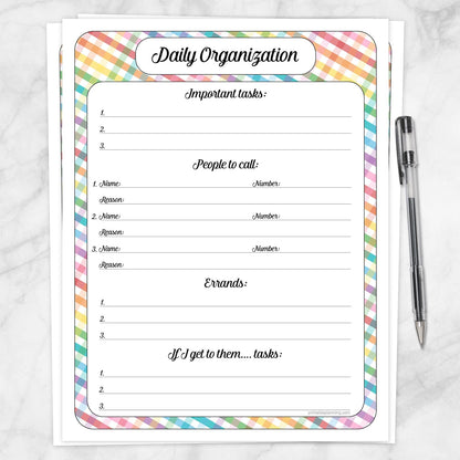 A printable Rainbow Gingham Daily Planner for Priorities, Calls, Errands & Tasks page shown on a marble surface with a pen.