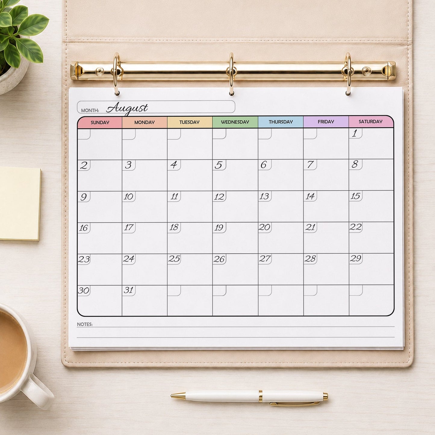 A printed rainbow undated monthly calendar (printable) page, with dates written in, shown in a beige binder on a table with a plant, sticky notes, coffee, and a pen.