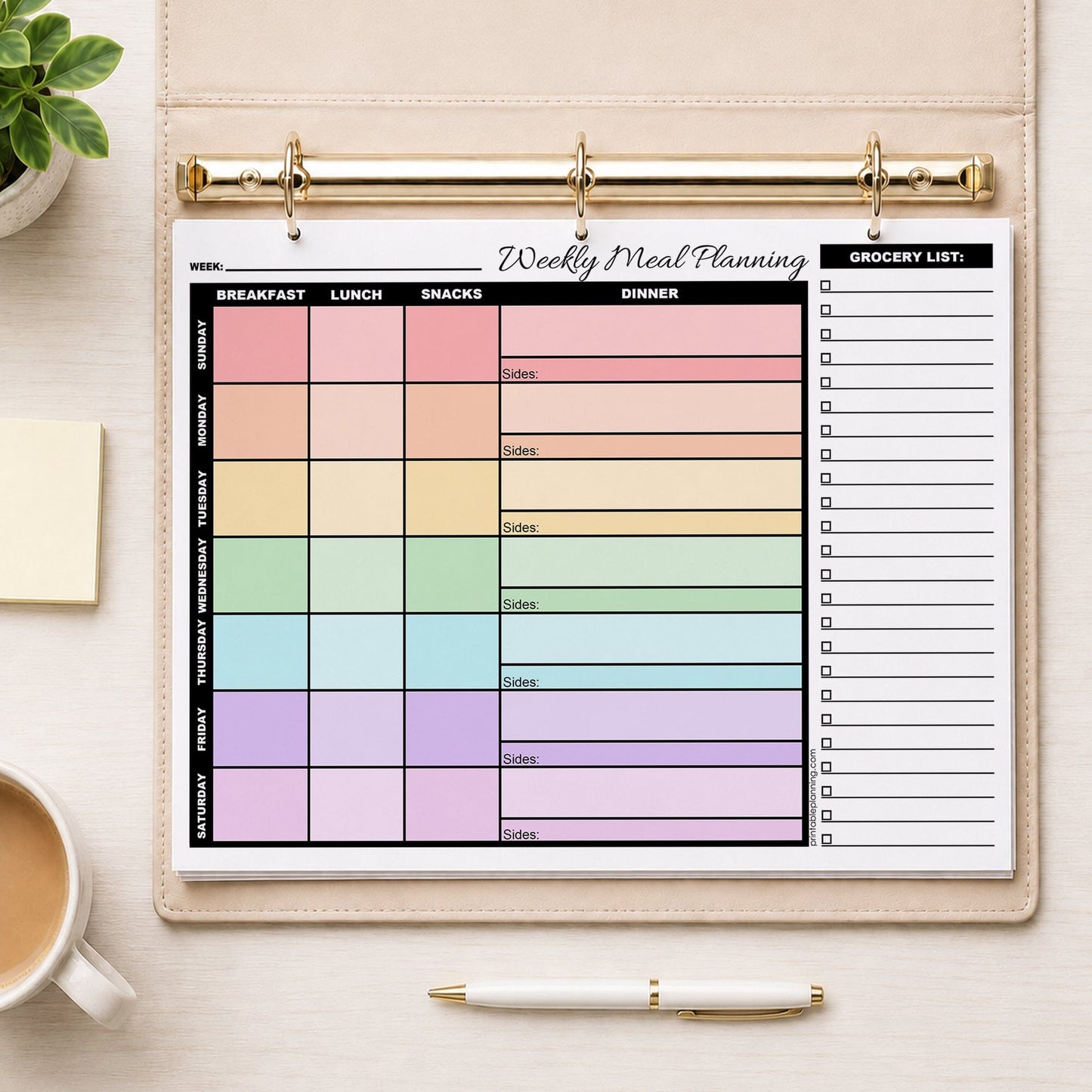 Rainbow Weekly Meal Planner with Grocery List (printable page) shown in a beige binder on a desk with a plant, coffee, notes, and a pen.