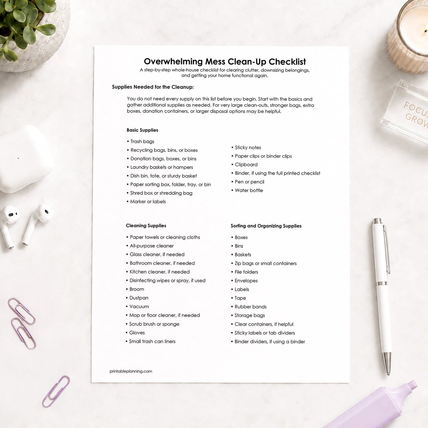 Printed page of the printable Supplies Needed for the Overwhelming Mess Clean-Up Checklist, shown on a light desk with a plant, earbuds, paperclips, highlighter, and a pen.
