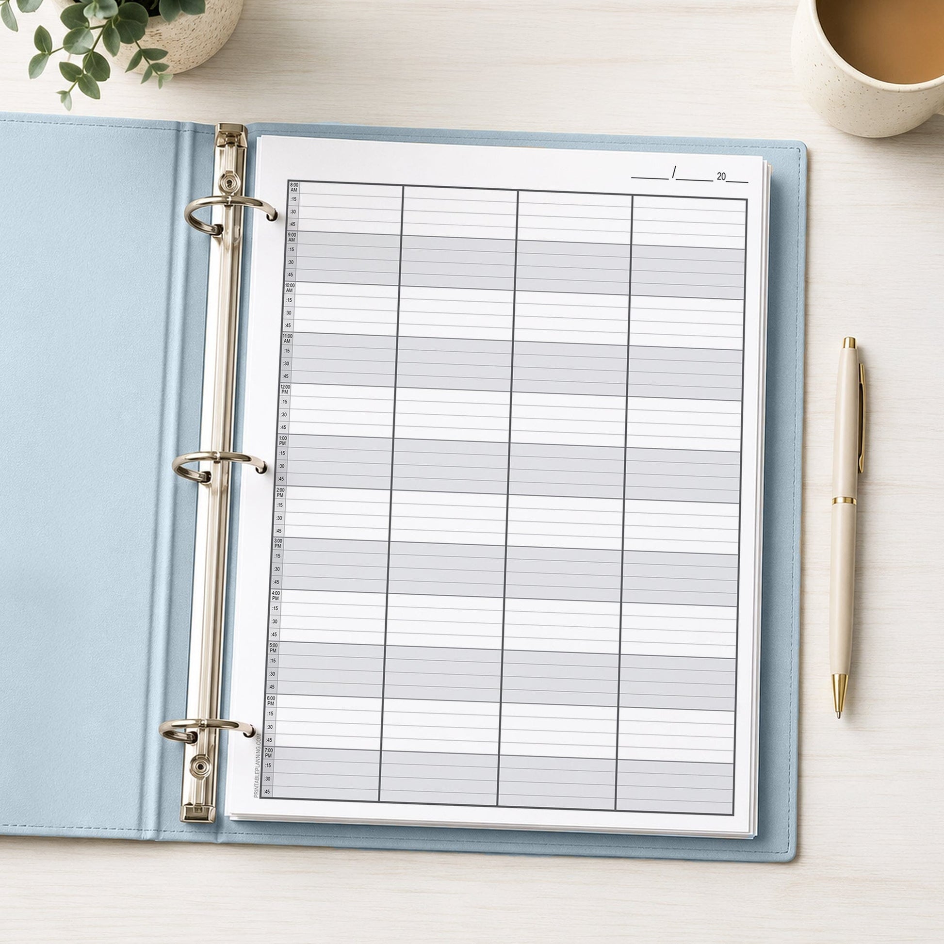 Schedule Sheet in 15 Minute Increments, 4 Columns (printable page) shown in a light blue binder on a desk with  plant, coffee, and a pen.