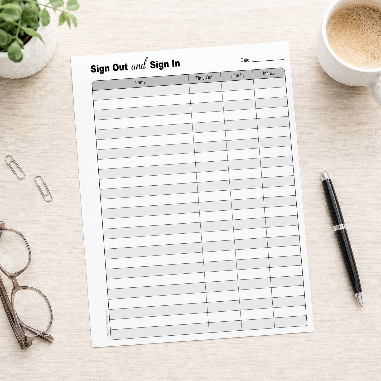 The printed Sign Out and Sign In Sheet (printable page) shown on a table with a plant, glasses, paperclips, coffee, and a pen.