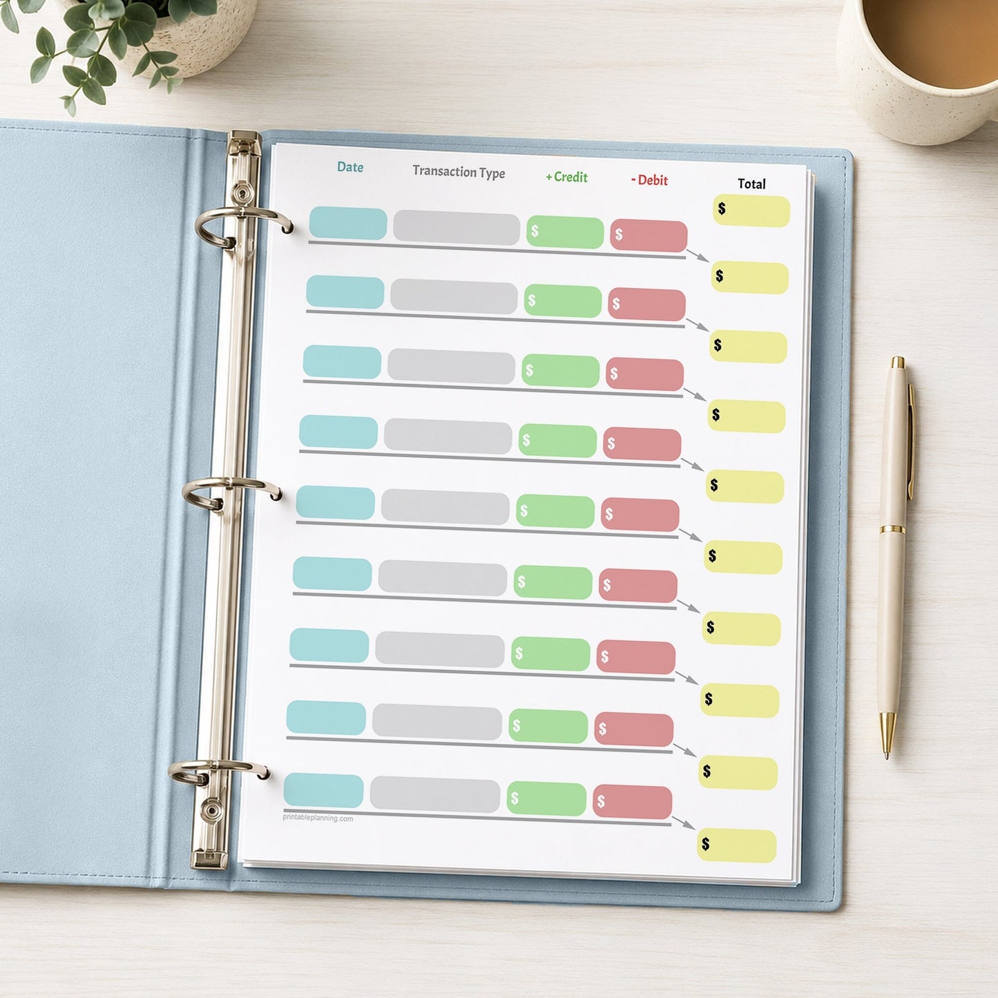 Simple Color-Coded Financial Transaction Register (printable page) shown in a light blue binder with a beverage, plant, and a pen.
