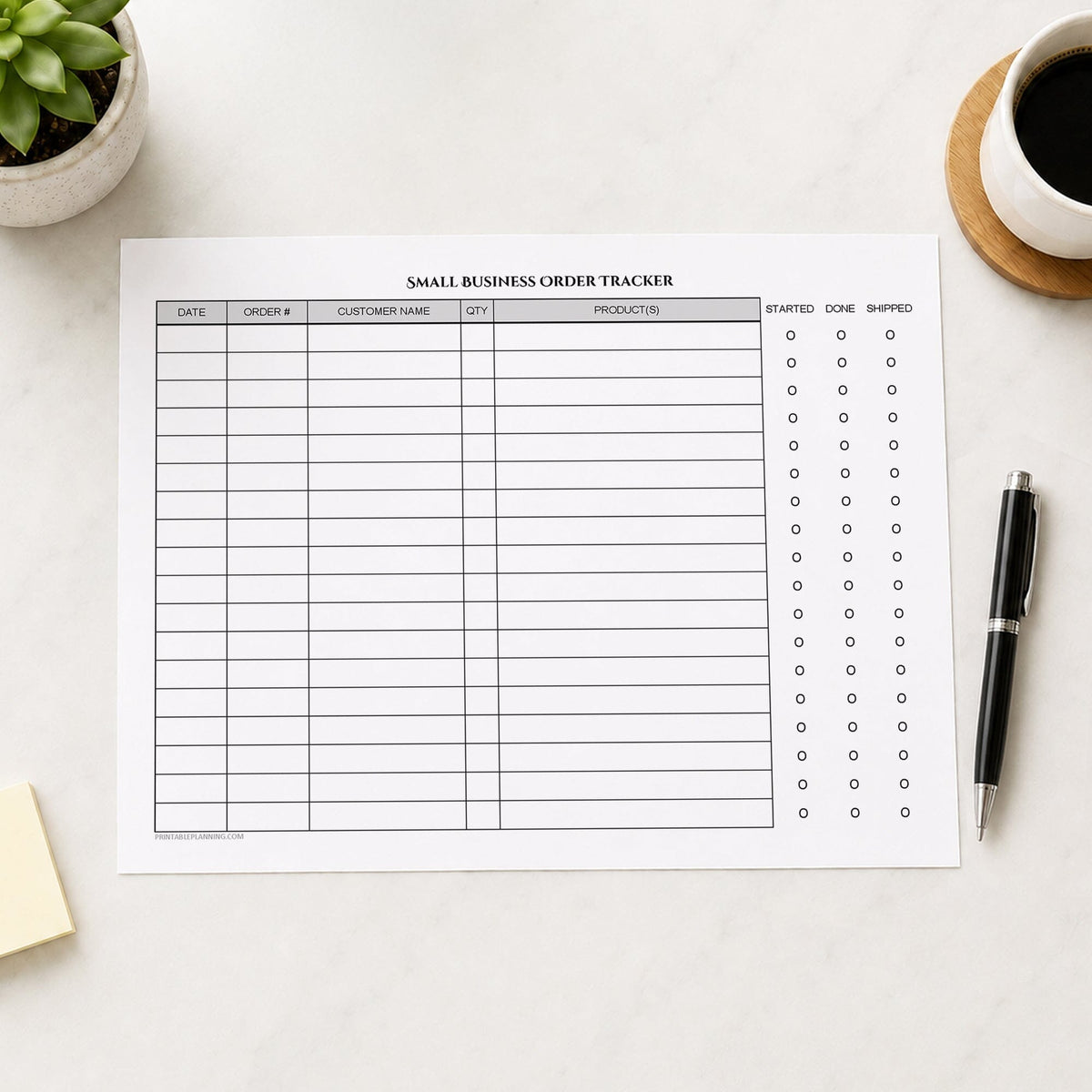 A printed Small Business Order Tracker with Order Status Checklist (printable) page shown on a desk with a plant, sticky notes, coffee, and a pen.