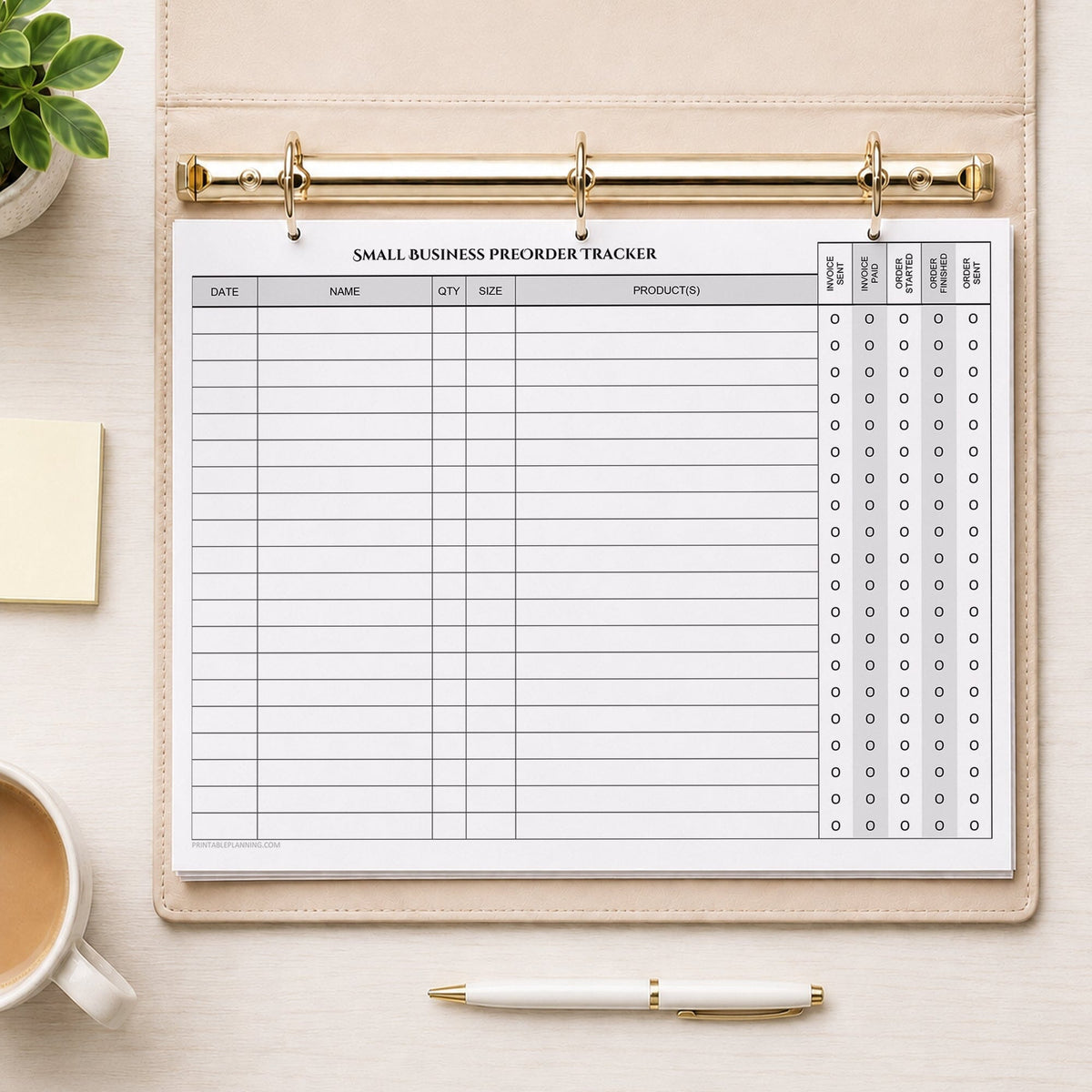 The printed Small Business Preorder Tracker with Payment & Order Status Checklist (printable) page shown in a beige binder on a desk with a plant, sticky notes, coffee, and a pen.