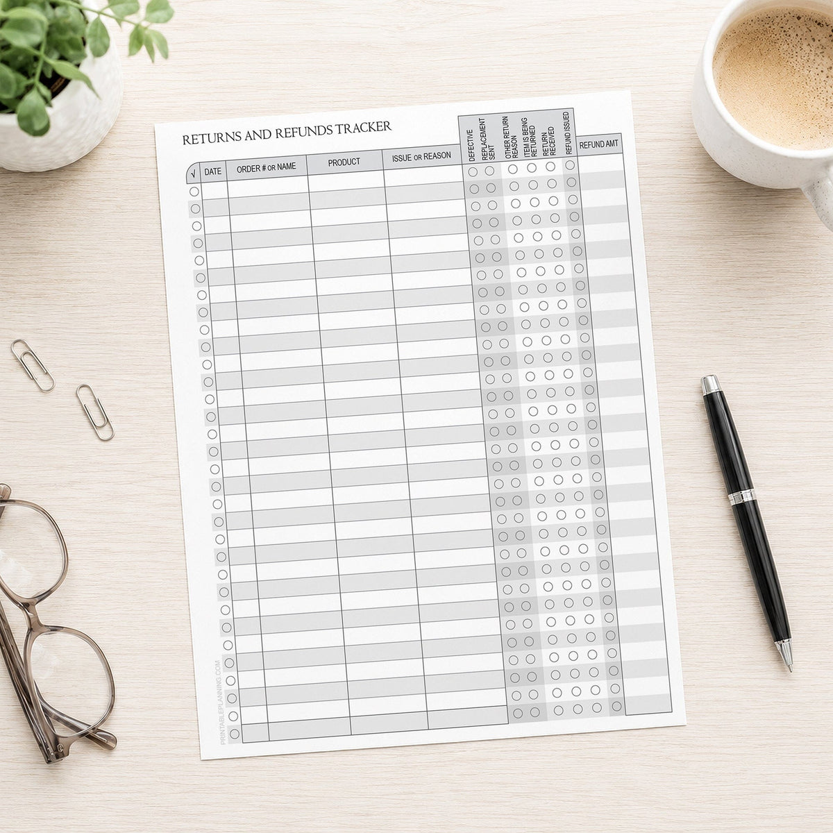 A printed page of the Small Business Return & Refund Tracker with Status Checklist shown on a desk with a plant, paperclips, glasses, coffee, and a pen.