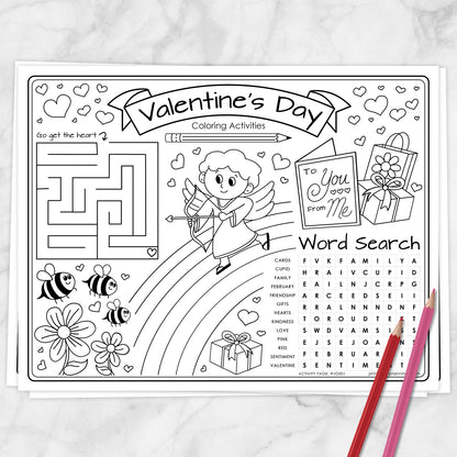 A Valentine's Day coloring activities sheet with black line art on white paper, featuring a maze, cartoon cupid, flowers, bees, a 'To You from Me' card, gift box, word search, and two colored pencils on a light marble surface.