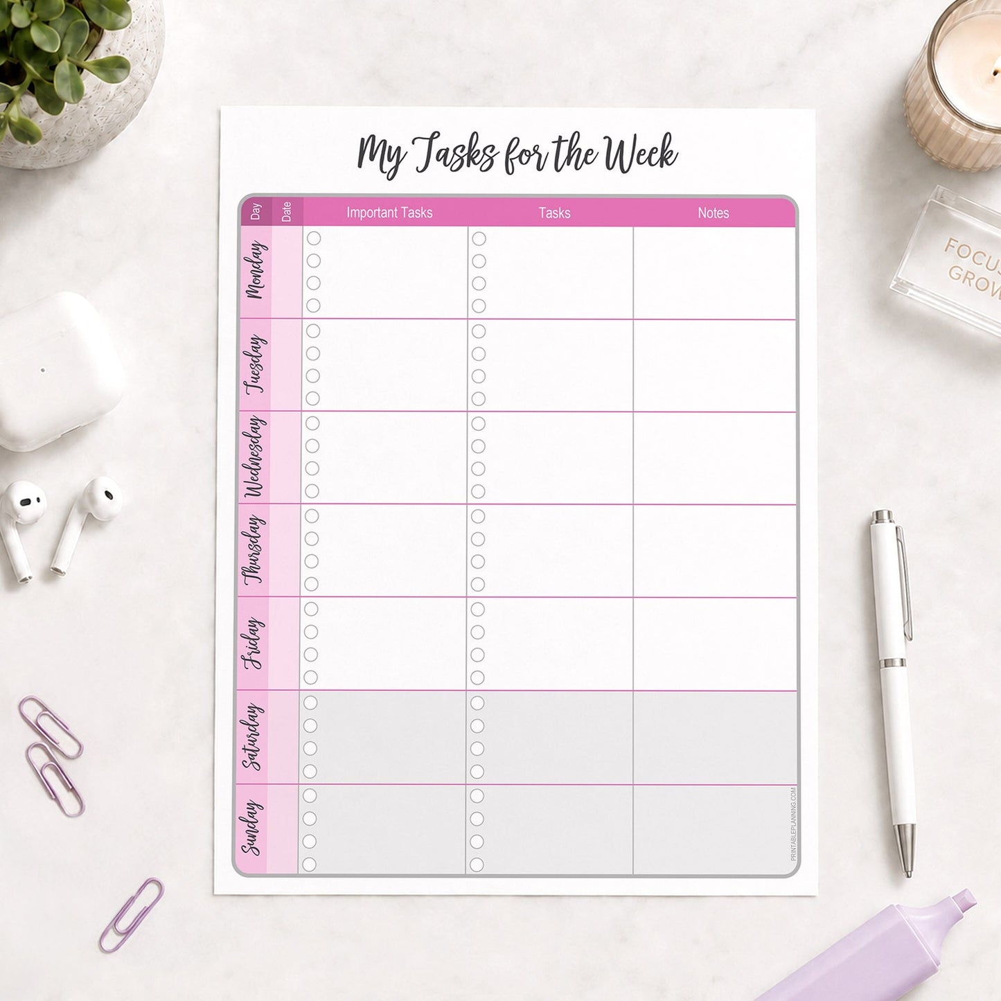 The printed Pink Weekly Task Planner with Priorities, Checklists & Notes (printable) page shown on a desk with a plant, earbuds, paperclips, highlighter, and a pen.