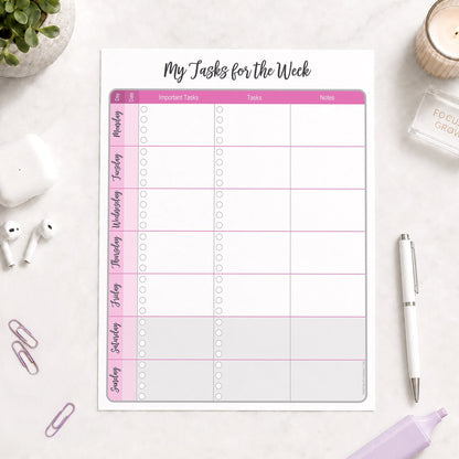 The printed Pink Weekly Task Planner with Priorities, Checklists & Notes (printable) page shown on a desk with a plant, earbuds, paperclips, highlighter, and a pen.