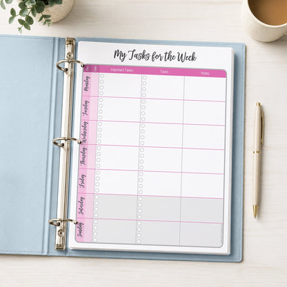 The printed Pink Weekly Task Planner with Priorities, Checklists & Notes (printable) page shown in a light blue binder on a desk with a plant, coffee, and a pen.