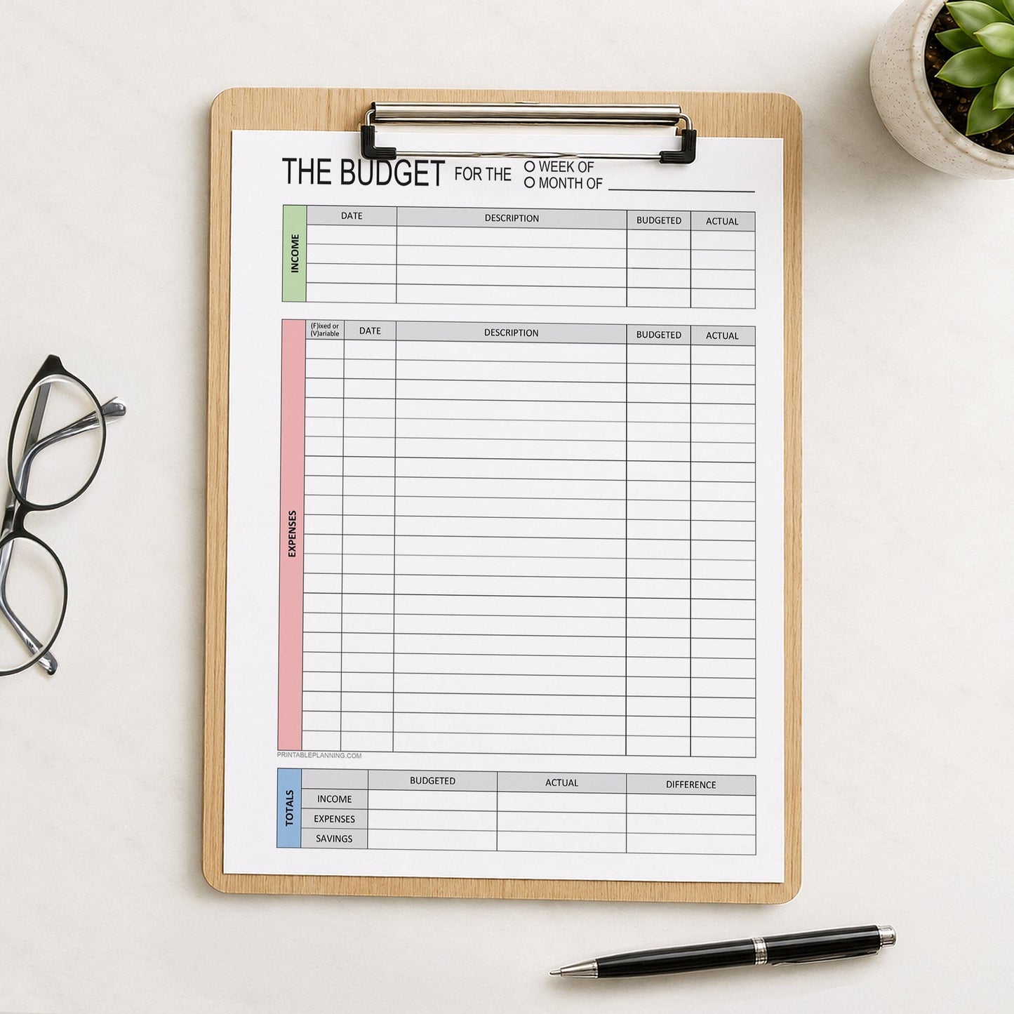 A printed page of the Weekly or Monthly Budget Worksheet - Printable Income and Expense Tracker shown on a wooden clipboard on a table with a plant, glasses, and a pen.