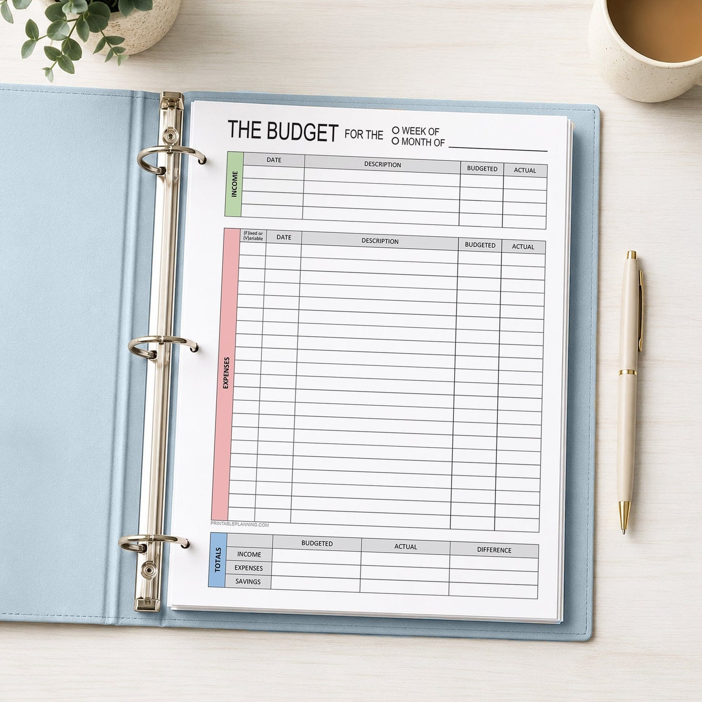 A printed page of the Weekly or Monthly Budget Worksheet - Printable Income and Expense Tracker shown in a light blue binder on a desk with a plant, coffee, and a pen.