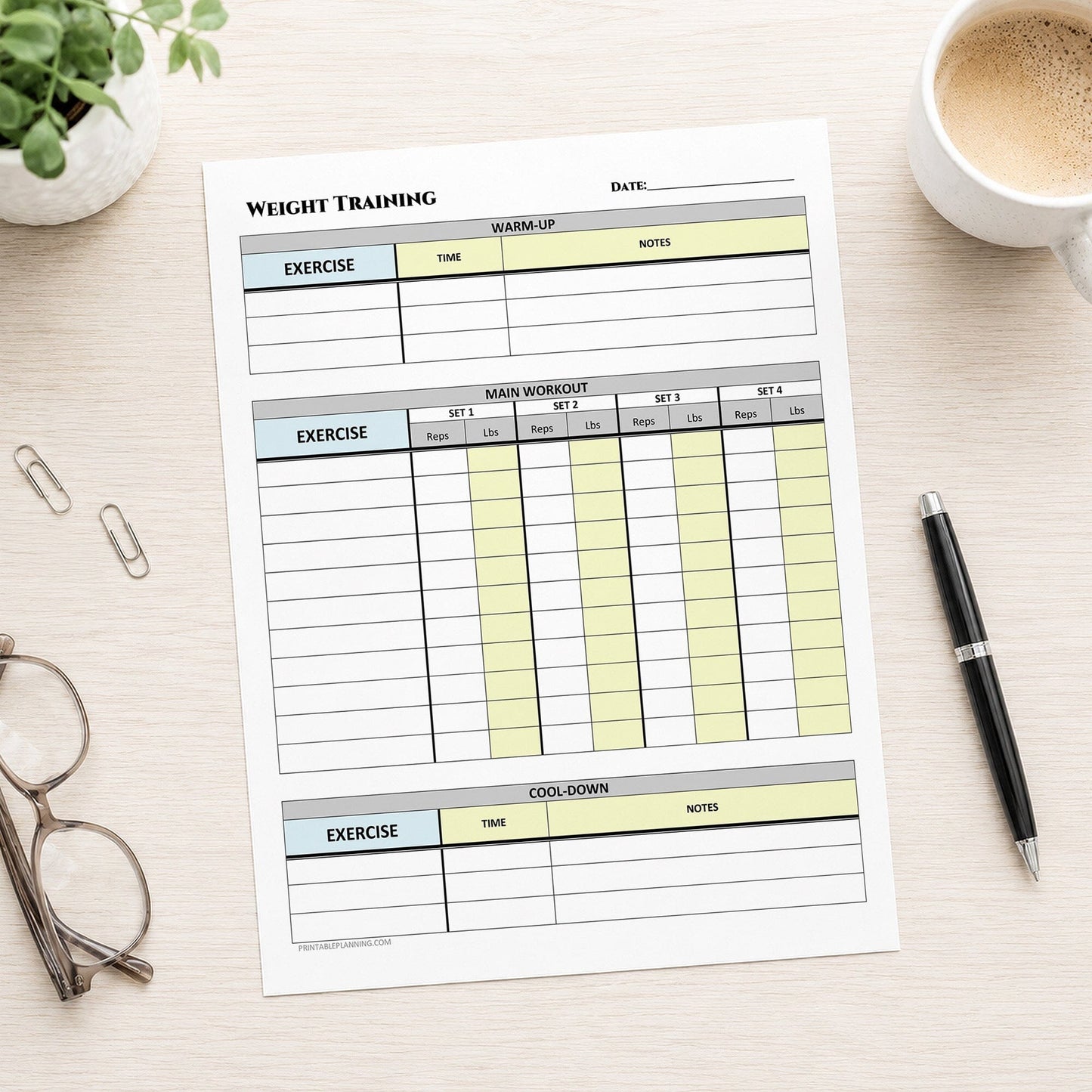 A printed Weight Training Workout Log with Warm-Up and Cool-Down (printable page) shown on a desk with a plant, coffee, glasses, paperclips, and a pen.