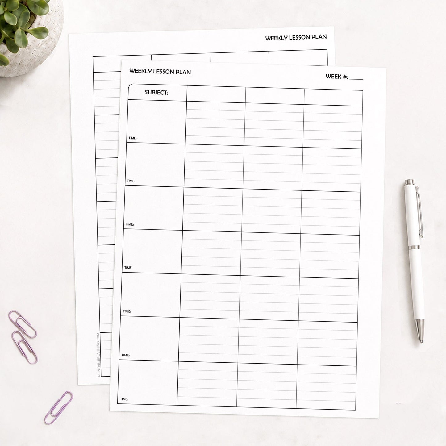 Two White Weekly Lesson Plan Pages for Teachers - Printable PDF sheets with black printed grid lines, arranged on a light surface with a white pen, purple paperclips, and a small plant in the corners.